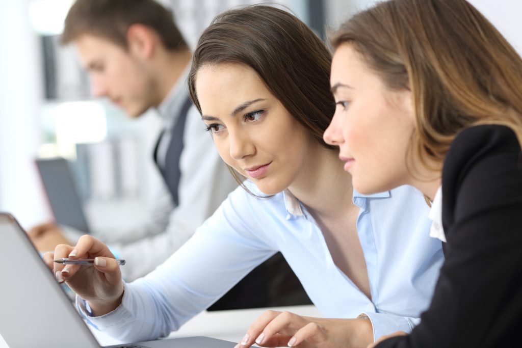 Two businesswomen working on line together with a laptop at office